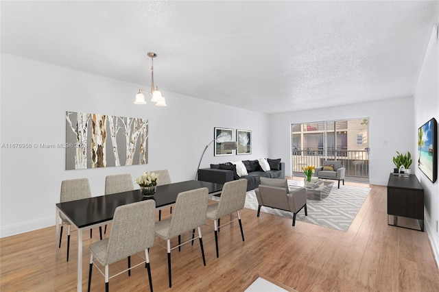 dining area featuring light hardwood / wood-style flooring, a textured ceiling, and an inviting chandelier