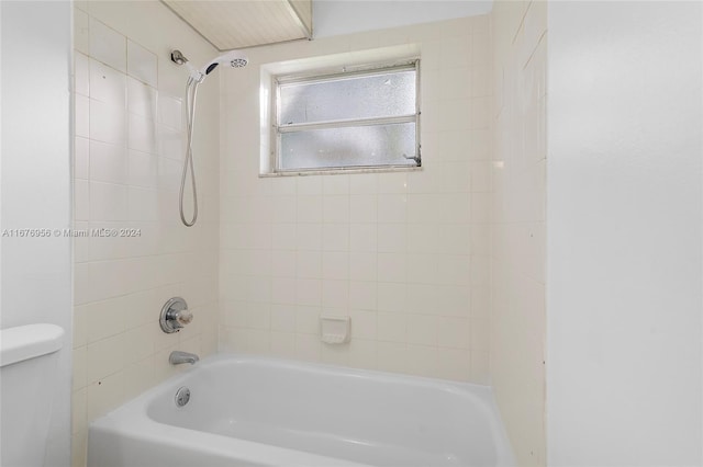 bathroom with toilet and tiled shower / bath