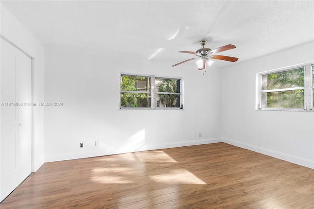 empty room featuring a textured ceiling, wood-type flooring, and ceiling fan