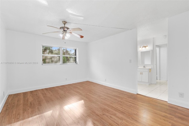 spare room with light hardwood / wood-style floors, a textured ceiling, and ceiling fan