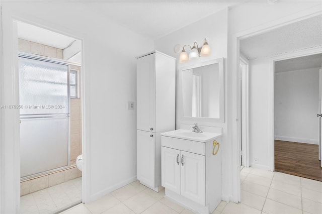 bathroom with vanity, toilet, tile patterned floors, and a shower with door