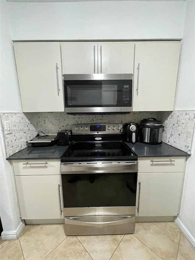 kitchen featuring stainless steel appliances, decorative backsplash, and white cabinets