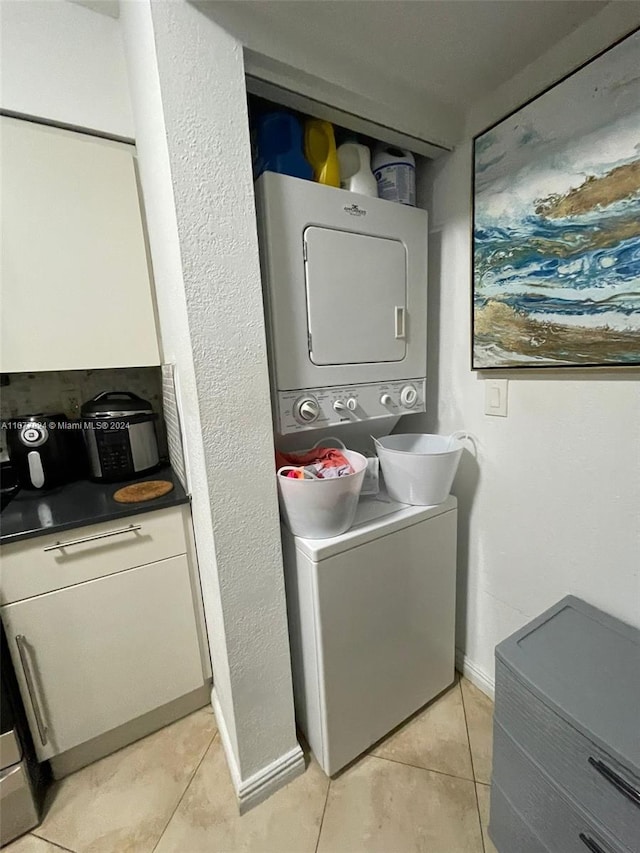 laundry area with light tile patterned flooring and stacked washing maching and dryer