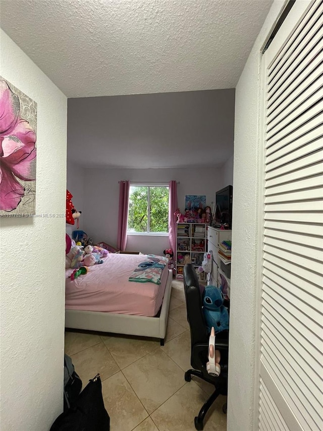 bedroom with a textured ceiling and light tile patterned floors