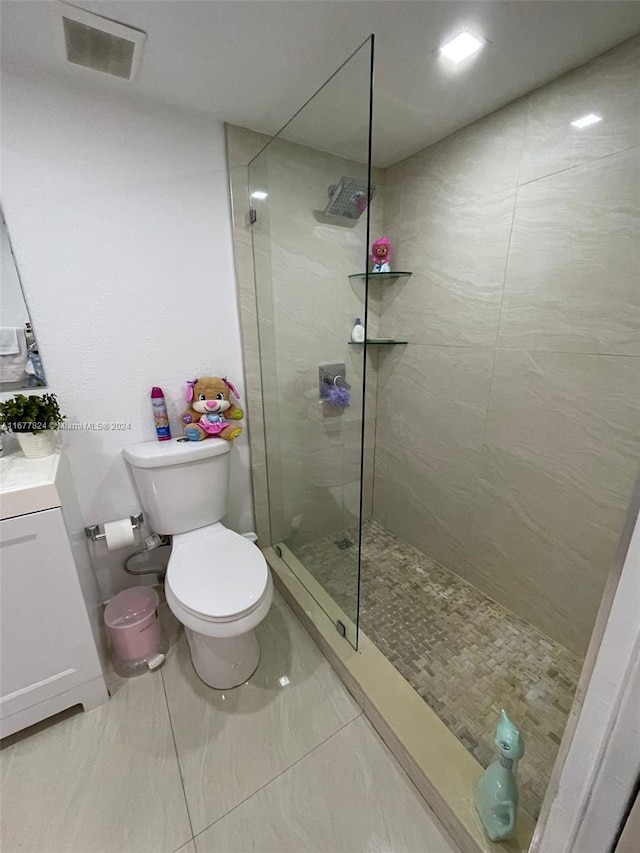 bathroom featuring a tile shower, toilet, and vanity