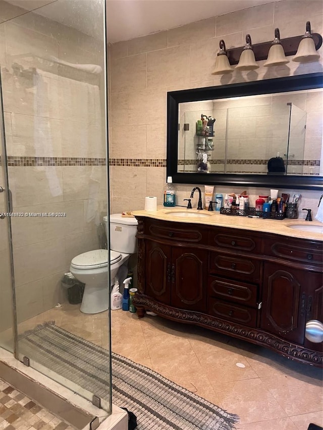 bathroom featuring tile walls, vanity, a shower with shower door, and toilet