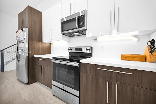 kitchen featuring white cabinets, dark brown cabinets, light tile patterned flooring, and appliances with stainless steel finishes