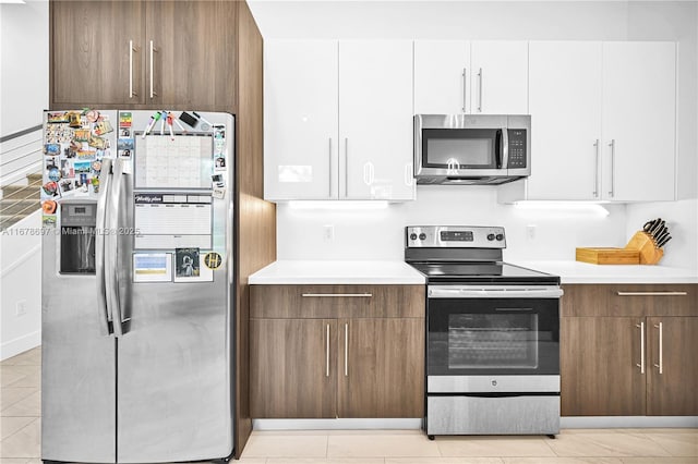 kitchen with white cabinetry, light tile patterned floors, and stainless steel appliances