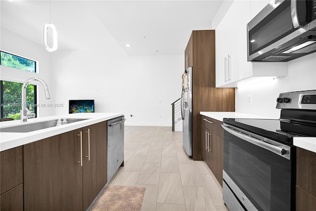 kitchen with appliances with stainless steel finishes, decorative light fixtures, white cabinetry, and sink