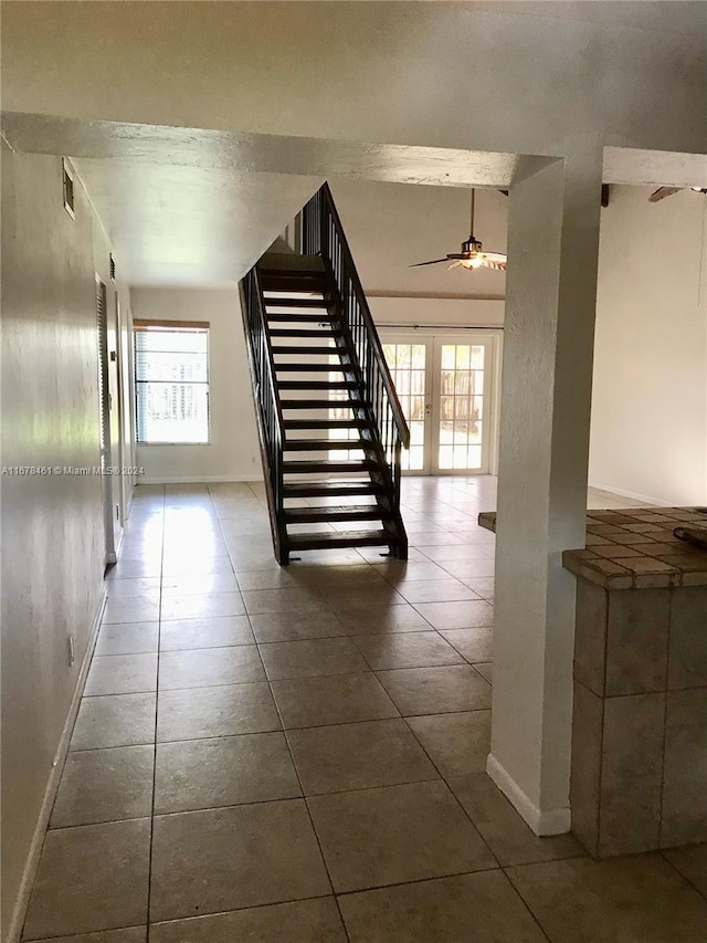 staircase with french doors, ceiling fan, tile patterned flooring, and plenty of natural light