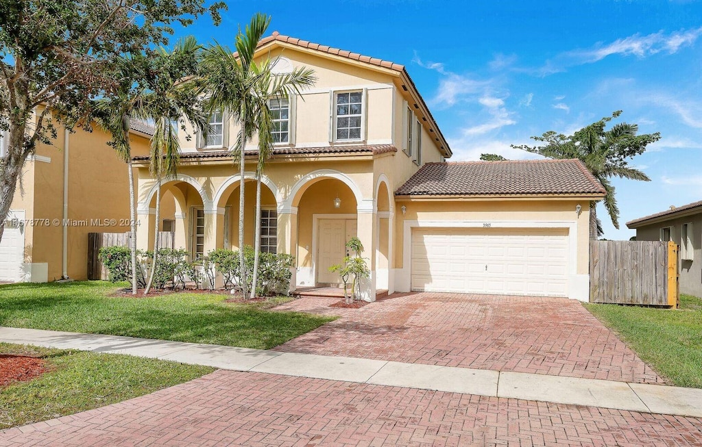 mediterranean / spanish home featuring a front yard and a garage