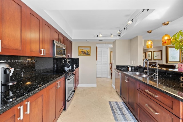 kitchen with tasteful backsplash, appliances with stainless steel finishes, sink, hanging light fixtures, and dark stone counters