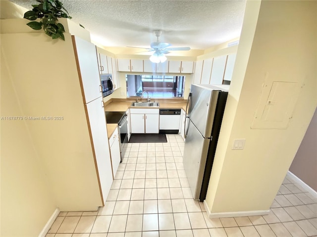 kitchen featuring a textured ceiling, appliances with stainless steel finishes, white cabinetry, sink, and light tile patterned flooring