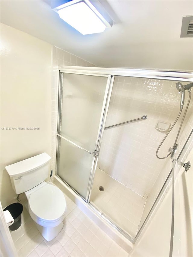 bathroom featuring tile patterned floors, toilet, walk in shower, and lofted ceiling