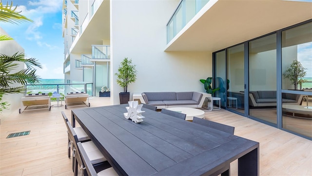 view of patio featuring outdoor lounge area, a water view, and a balcony