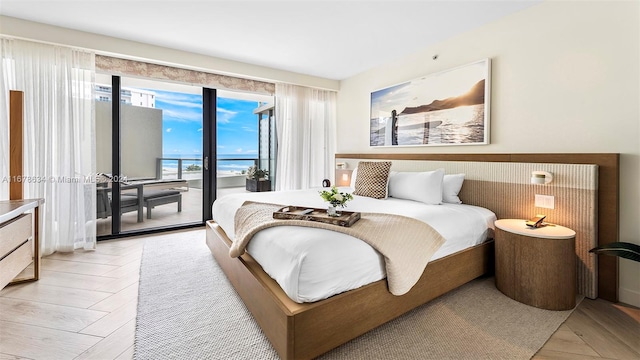 bedroom with a water view, access to exterior, and light wood-type flooring