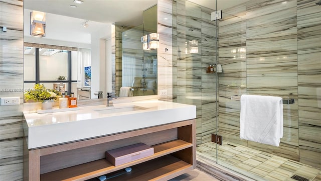 bathroom featuring a shower with door, vanity, and tile walls