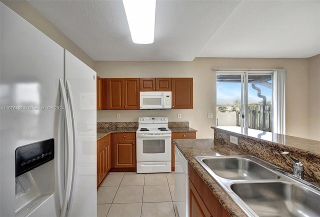 kitchen featuring white appliances, light tile patterned flooring, sink, a textured ceiling, and dark stone counters