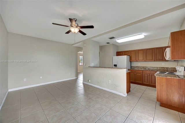 kitchen with light tile patterned floors, light stone countertops, white appliances, and ceiling fan