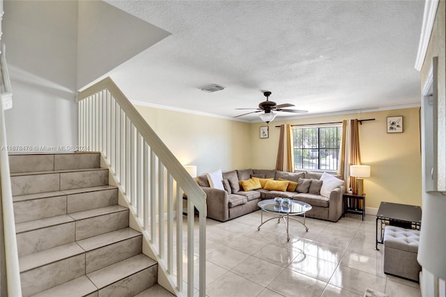 tiled living room featuring ceiling fan, ornamental molding, and a textured ceiling