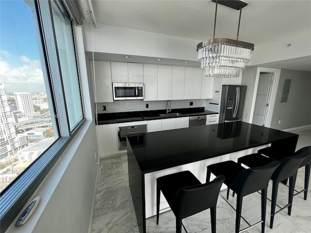 kitchen featuring sink, stainless steel appliances, decorative light fixtures, white cabinets, and an inviting chandelier