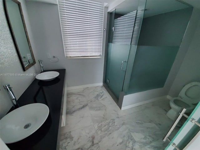 bathroom featuring a shower with door, vanity, and toilet