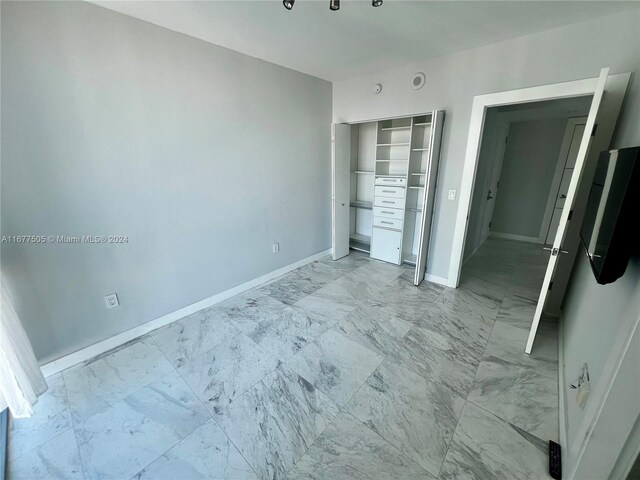 92 SW 3rd Unit 3605, Miami, FL 33130 - unfurnished bedroom featuring light marble finish flooring, baseboards, and a closet