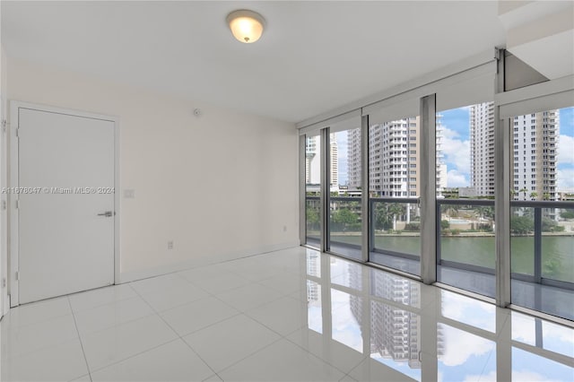 empty room featuring a water view, expansive windows, and light tile patterned floors