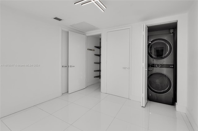 washroom with stacked washer / drying machine and light tile patterned floors