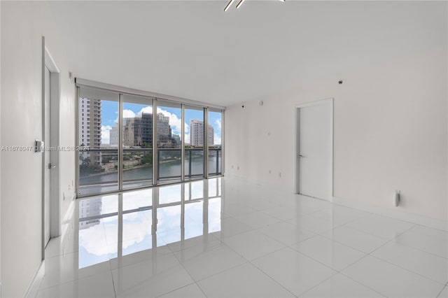 unfurnished room featuring a water view, floor to ceiling windows, and light tile patterned floors