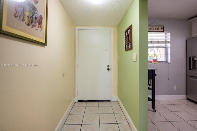 doorway featuring a textured ceiling and light tile patterned floors