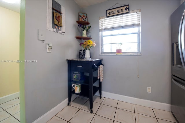 interior space featuring stainless steel refrigerator with ice dispenser, blue cabinets, and light tile patterned floors