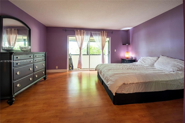 bedroom with hardwood / wood-style flooring, a textured ceiling, and access to exterior