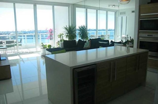 kitchen with a kitchen island, a water view, beverage cooler, and oven