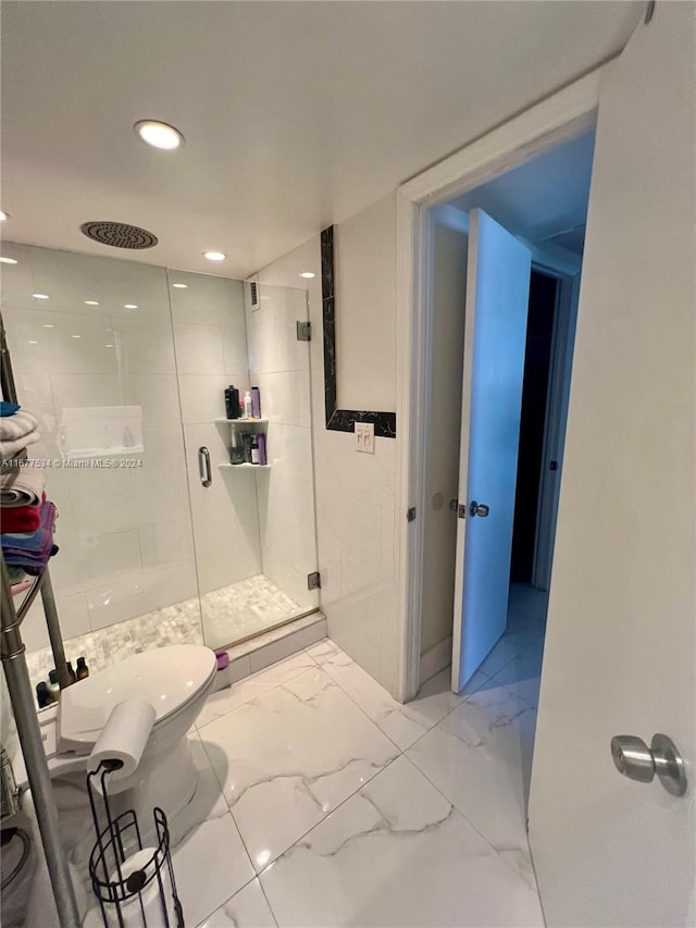 bathroom featuring a shower with door and toilet