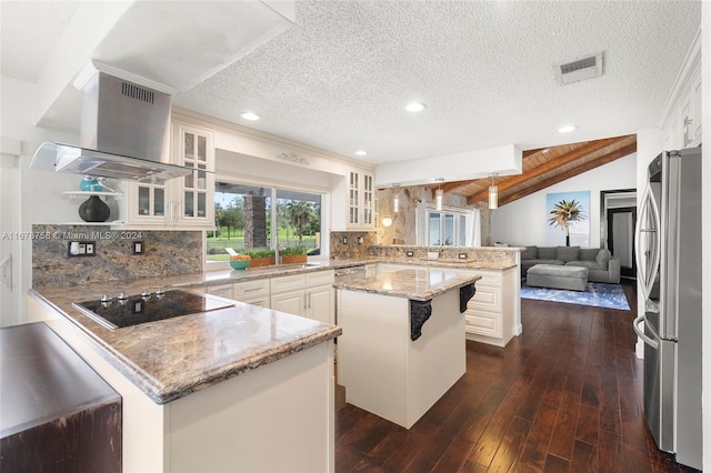 kitchen with stainless steel fridge, a textured ceiling, vaulted ceiling, black electric stovetop, and a center island