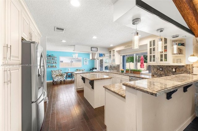 kitchen featuring a kitchen bar, appliances with stainless steel finishes, kitchen peninsula, and white cabinetry