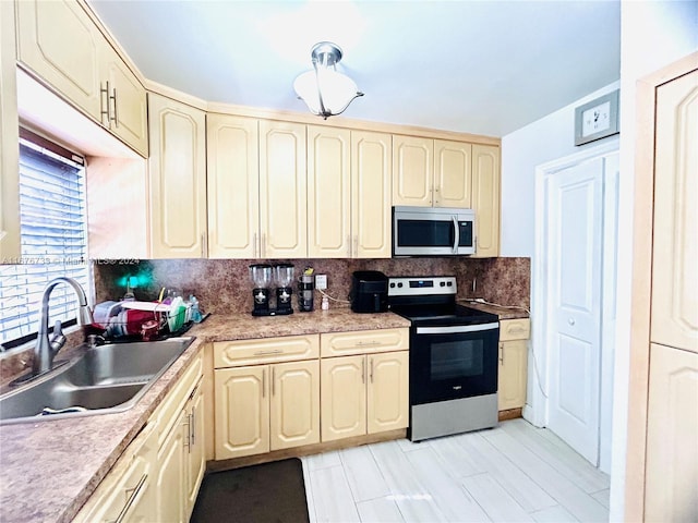 kitchen with decorative backsplash, sink, stainless steel appliances, and cream cabinets