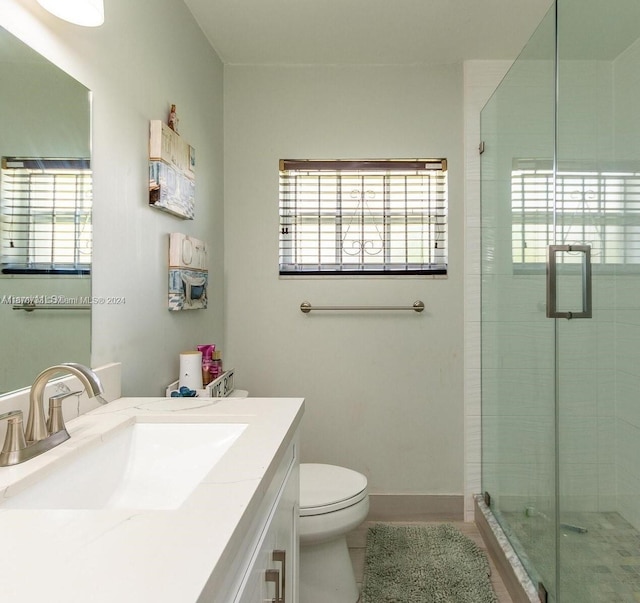 bathroom with tile patterned floors, vanity, toilet, and a shower with door