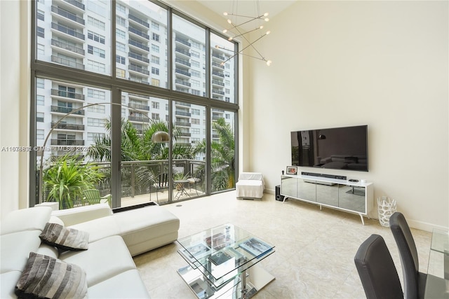 living room featuring a towering ceiling, a wealth of natural light, and an inviting chandelier