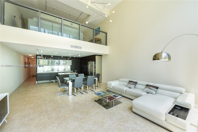 living room with a high ceiling, a notable chandelier, and rail lighting