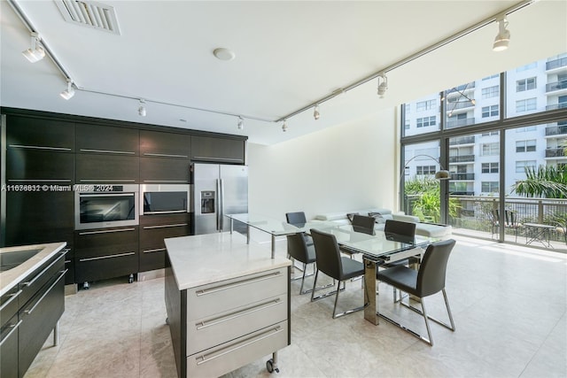 kitchen with appliances with stainless steel finishes, a healthy amount of sunlight, dark brown cabinets, and a kitchen island