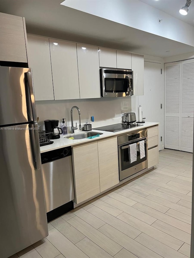 kitchen featuring appliances with stainless steel finishes, white cabinets, sink, and light wood-type flooring