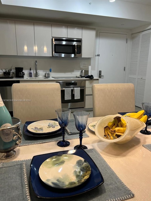 kitchen with appliances with stainless steel finishes, white cabinets, and sink