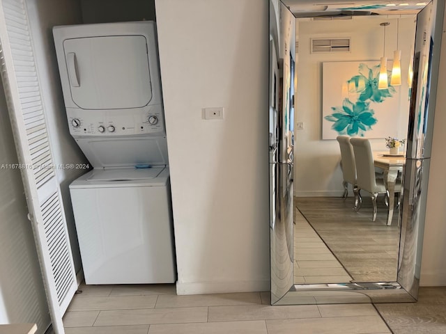 clothes washing area with stacked washer and dryer and light wood-type flooring