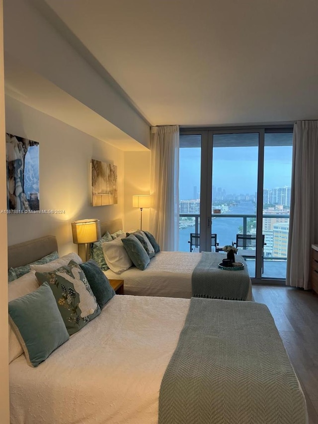 bedroom with a water view, access to exterior, expansive windows, and hardwood / wood-style floors