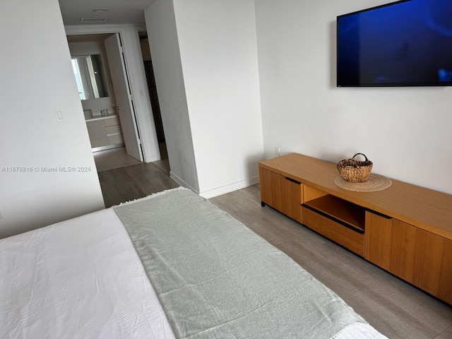 bedroom with connected bathroom and light wood-type flooring