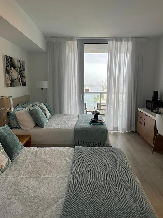 bedroom with a water view and hardwood / wood-style floors