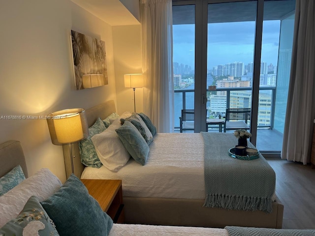 bedroom featuring a water view, hardwood / wood-style flooring, and access to exterior