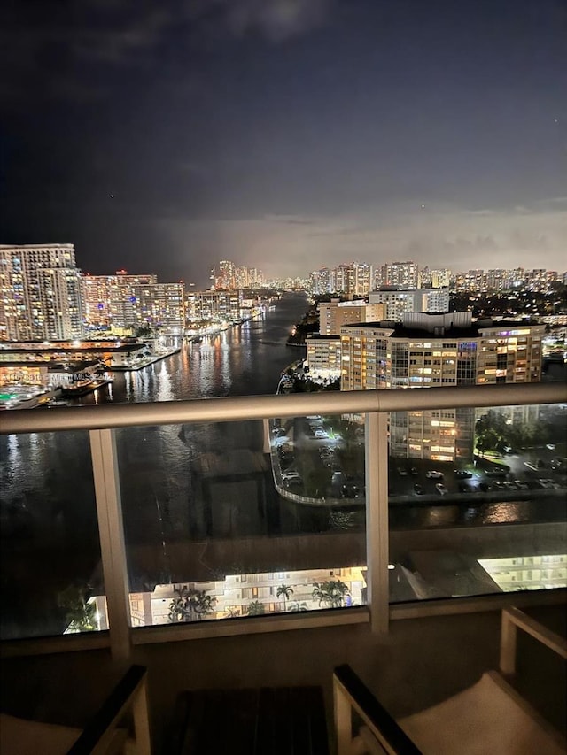 balcony at night featuring a water view